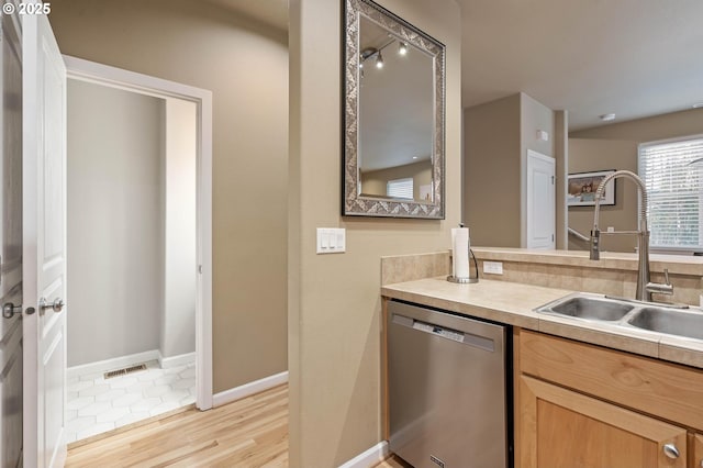 kitchen featuring a sink, baseboards, light wood-style floors, light countertops, and dishwasher