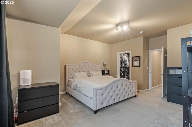 bedroom featuring light carpet, a spacious closet, baseboards, and a closet