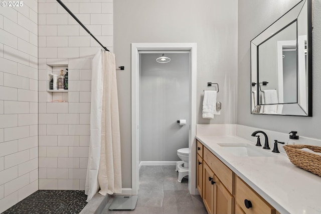 bathroom featuring toilet, baseboards, a tile shower, and vanity