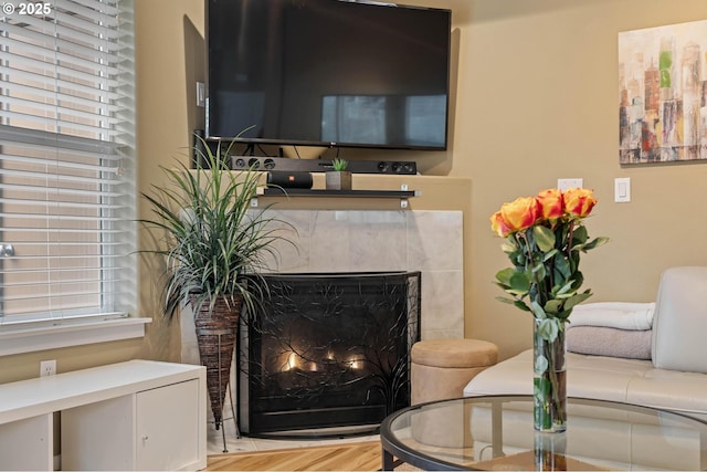 living area with a lit fireplace and wood finished floors