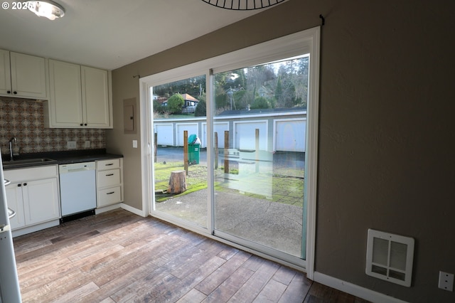 kitchen with decorative backsplash, dishwasher, white cabinets, and sink