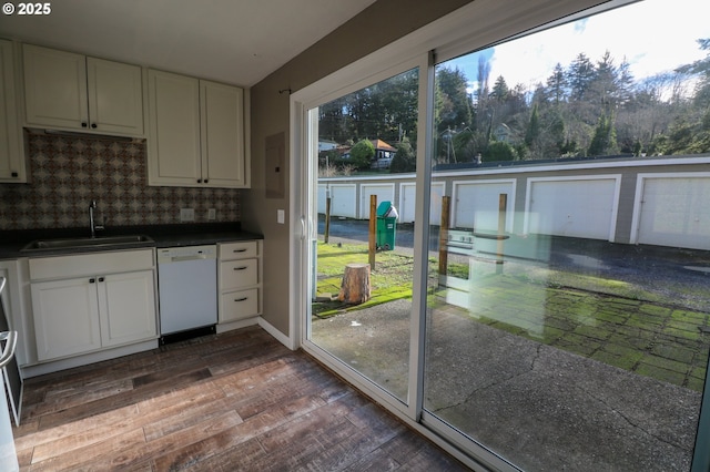 kitchen featuring white dishwasher, backsplash, white cabinets, and sink