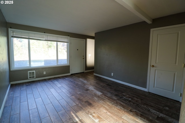 spare room featuring beam ceiling and dark wood-type flooring