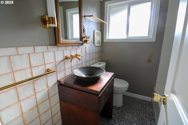 bathroom featuring tile patterned flooring, vanity, toilet, and tile walls