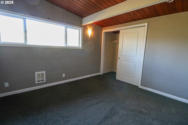 carpeted spare room featuring vaulted ceiling with beams, a healthy amount of sunlight, and wooden ceiling