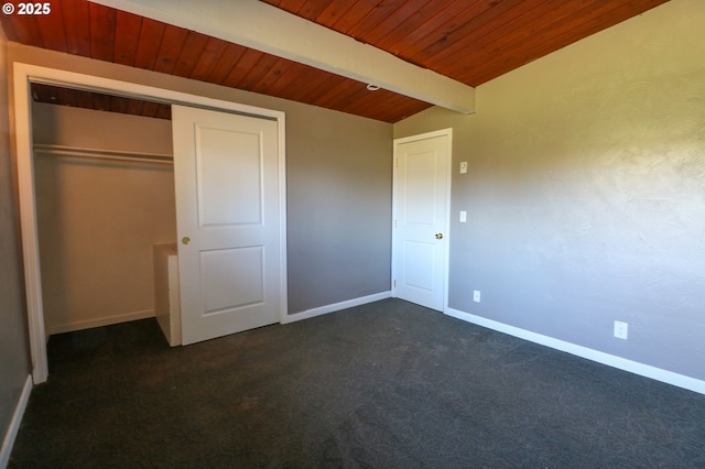 unfurnished bedroom with dark colored carpet, lofted ceiling with beams, a closet, and wooden ceiling