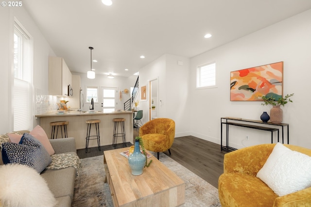 living room featuring baseboards, recessed lighting, wood finished floors, and a healthy amount of sunlight