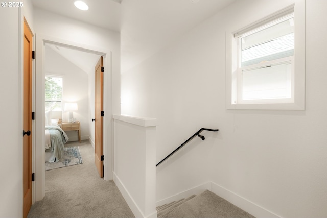 hall with lofted ceiling, baseboards, carpet flooring, and an upstairs landing