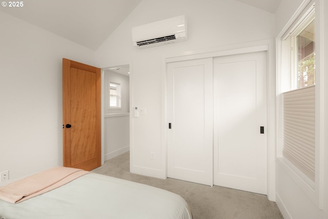 bedroom with a wall unit AC, light carpet, baseboards, vaulted ceiling, and a closet