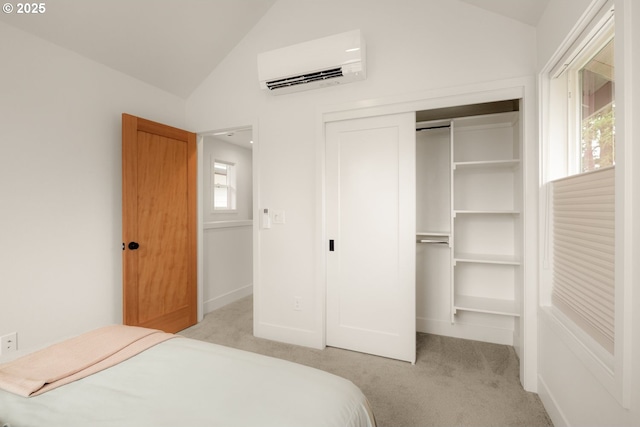 carpeted bedroom with lofted ceiling, a closet, baseboards, and a wall mounted AC