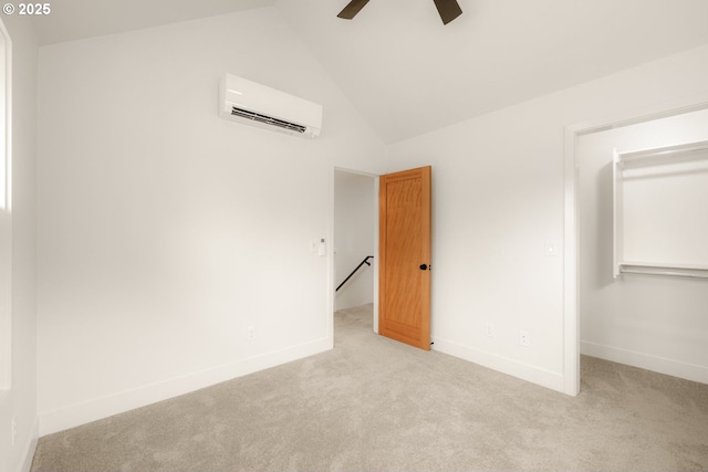 unfurnished bedroom featuring lofted ceiling, a closet, an AC wall unit, and light colored carpet