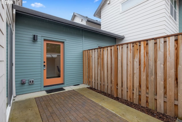 view of exterior entry with a patio area and fence