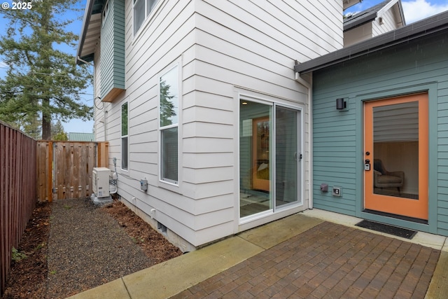 view of exterior entry with fence and a patio