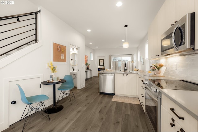 kitchen with stainless steel appliances, a peninsula, light countertops, dark wood-style floors, and tasteful backsplash