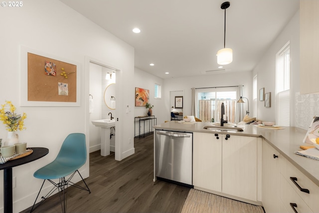 kitchen featuring a peninsula, a sink, light countertops, stainless steel dishwasher, and dark wood finished floors