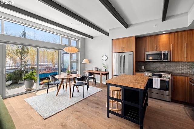 323 NW 13th Ave Unit 404, Portland, OR 97209 - kitchen with stainless steel appliances, brown cabinets, tasteful backsplash, beam ceiling, and dark countertops