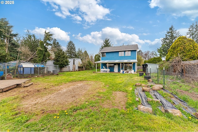 back of house featuring a yard, fence, and an outdoor structure