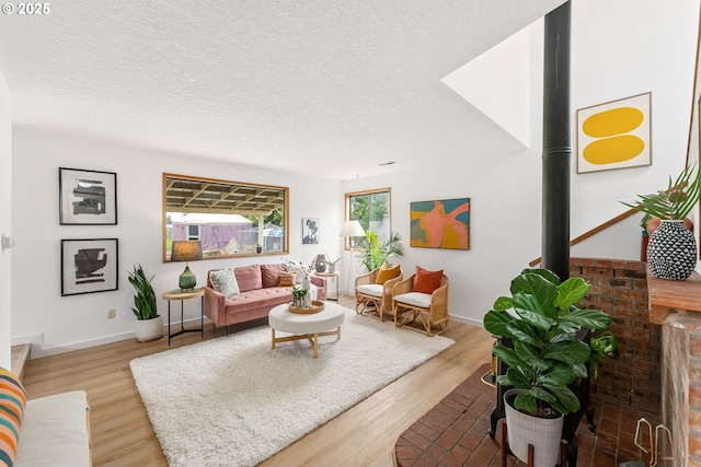 living room featuring light wood-style flooring, a textured ceiling, and baseboards
