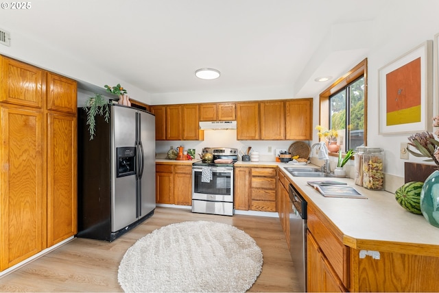 kitchen featuring light countertops, under cabinet range hood, a sink, and stainless steel appliances