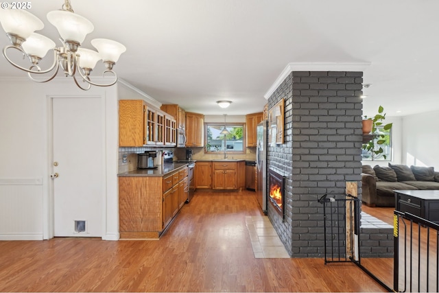 kitchen featuring brown cabinetry, a chandelier, a sink, light wood-style flooring, and stainless steel appliances