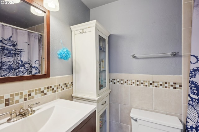 full bath featuring wainscoting, vanity, toilet, tile walls, and curtained shower