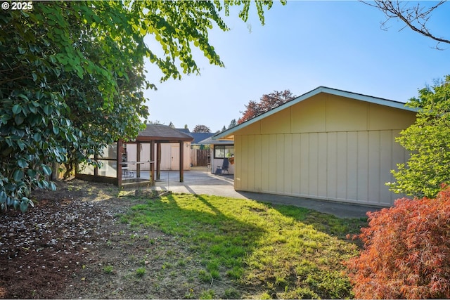view of property exterior featuring a yard, a patio, an outbuilding, and a storage unit