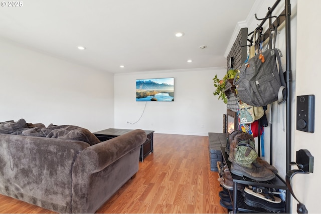 living area featuring crown molding, baseboards, light wood-style floors, and recessed lighting