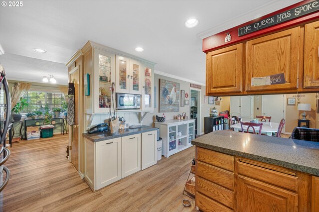 20685 SW Siletz Ct, Tualatin, OR 97062 - kitchen with stainless steel microwave, light wood-type flooring, ornamental molding, glass insert cabinets, and recessed lighting