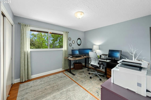 office space featuring wood finished floors, baseboards, and a textured ceiling