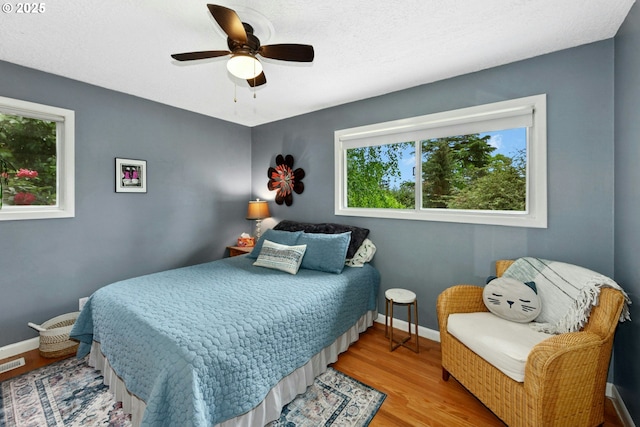 bedroom featuring wood finished floors, baseboards, and ceiling fan