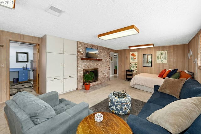 living room with wood walls, a textured ceiling, carpet flooring, and a fireplace