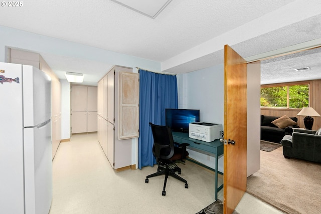 office area featuring a textured ceiling and light carpet