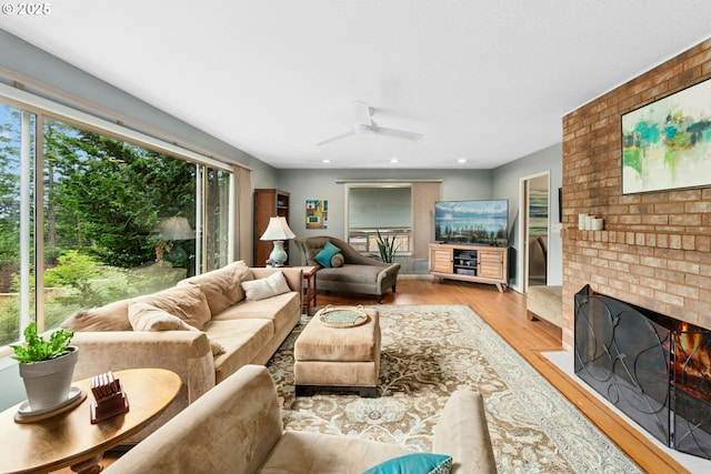 living area with wood finished floors, a ceiling fan, a fireplace, and recessed lighting