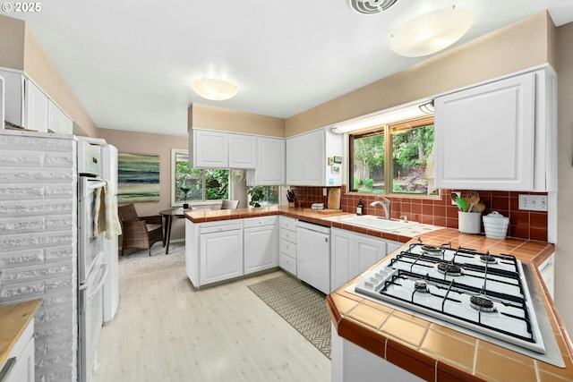 kitchen featuring dishwasher, a sink, gas cooktop, and tile countertops