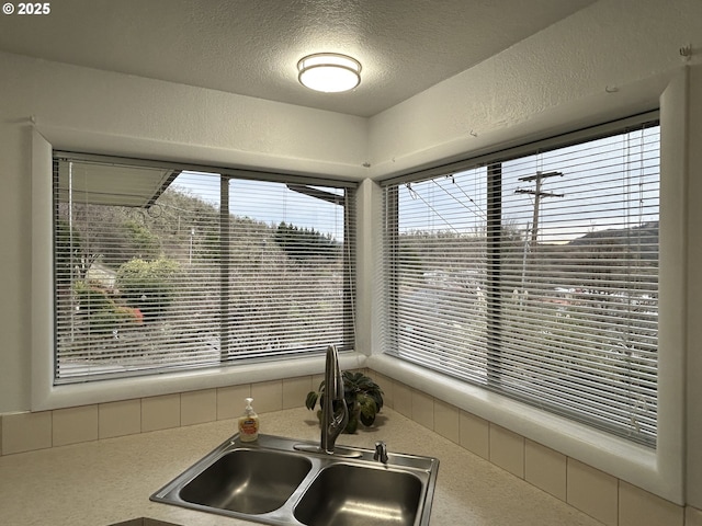 kitchen with a textured wall, light countertops, a sink, and a textured ceiling