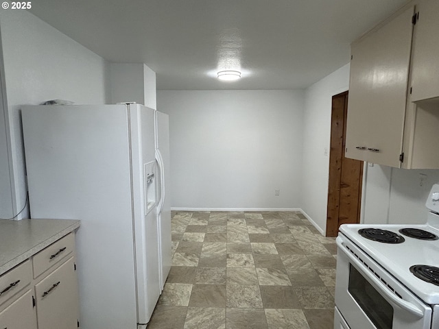 kitchen with white appliances, baseboards, white cabinets, stone finish floor, and light countertops