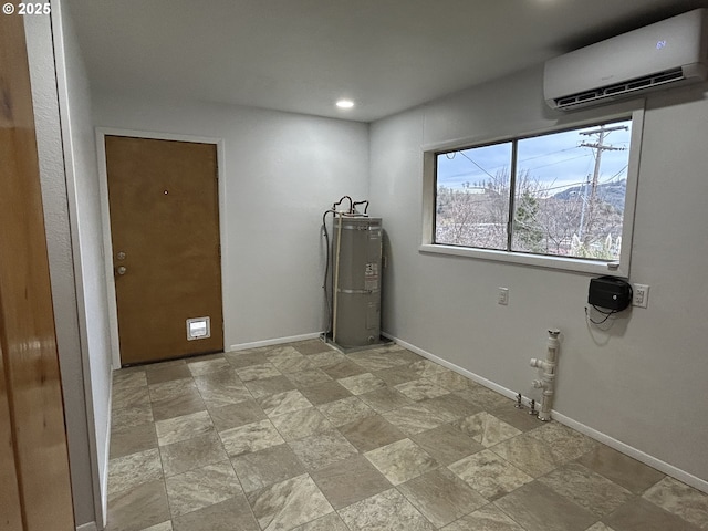 clothes washing area with water heater, stone finish flooring, a wall unit AC, and baseboards