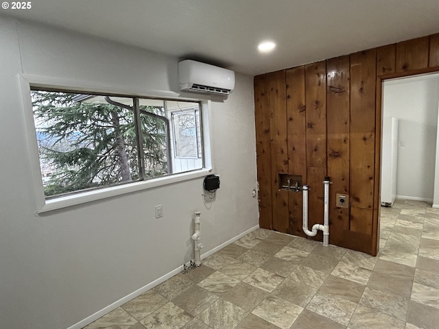 interior space featuring laundry area, a wall unit AC, and baseboards