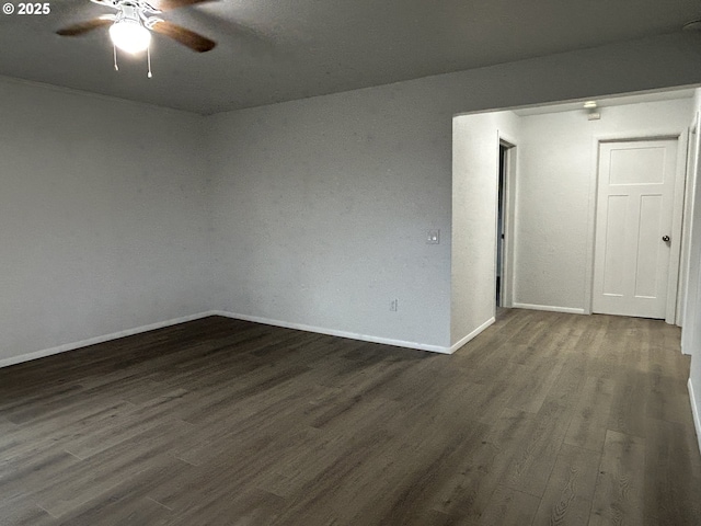 spare room featuring dark wood finished floors, a ceiling fan, and baseboards