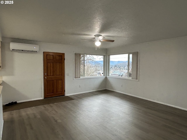 empty room with baseboards, dark wood-type flooring, a textured ceiling, a mountain view, and a wall mounted AC