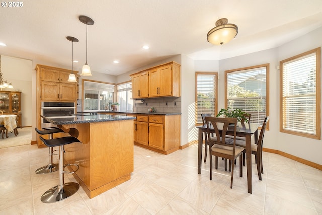 12015 SE Regal Ct, Clackamas, OR 97015 - kitchen with stainless steel oven, a kitchen island, a kitchen bar, tasteful backsplash, and pendant lighting
