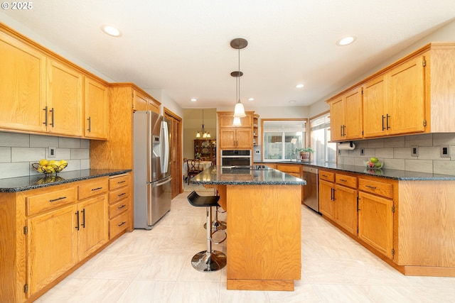 12015 SE Regal Ct, Clackamas, OR 97015 - kitchen featuring appliances with stainless steel finishes, a kitchen island, a kitchen bar, dark stone counters, and recessed lighting