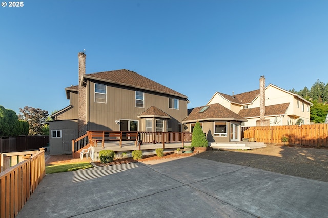 12015 SE Regal Ct, Clackamas, OR 97015 - rear view of property with a deck, a patio, a fenced backyard, and a chimney