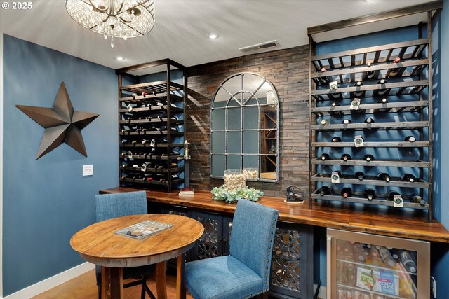 wine room with an inviting chandelier, baseboards, wine cooler, visible vents, and recessed lighting