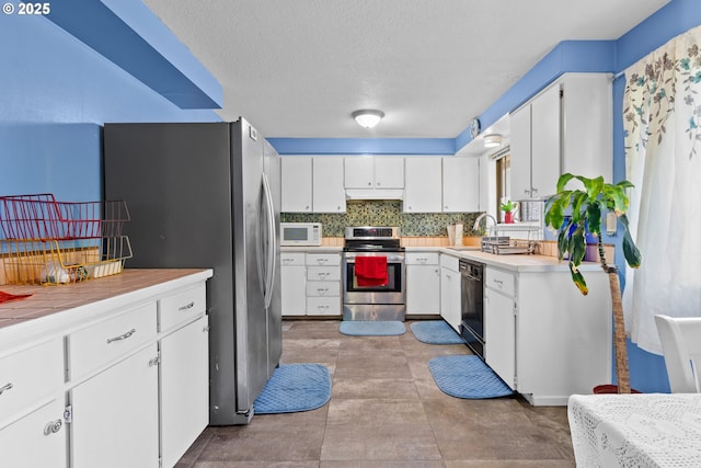 kitchen with tasteful backsplash, a textured ceiling, white cabinets, sink, and stainless steel appliances