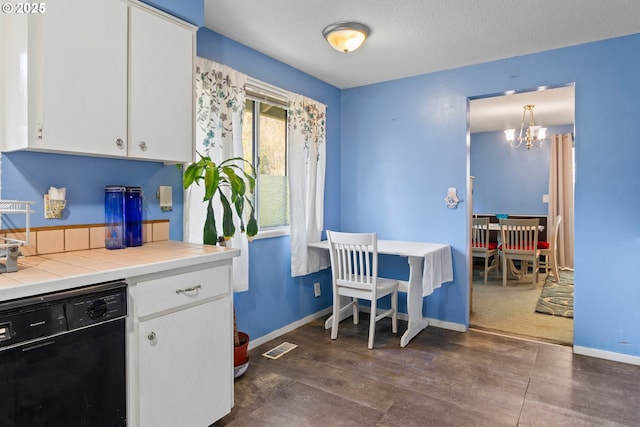 kitchen featuring black dishwasher, a chandelier, white cabinetry, hanging light fixtures, and tile countertops