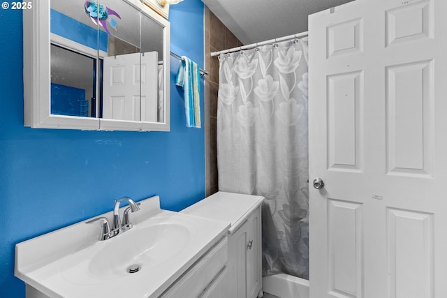 bathroom featuring a textured ceiling, walk in shower, and vanity