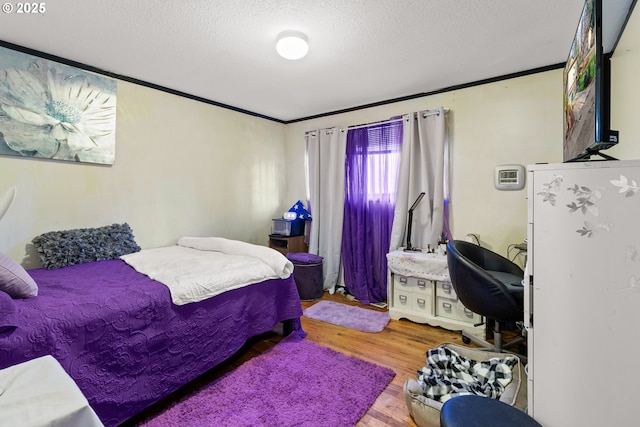 bedroom with crown molding, hardwood / wood-style floors, and a textured ceiling