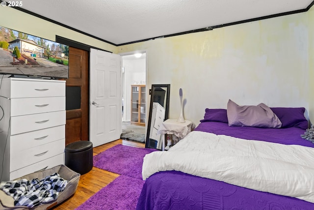 bedroom featuring light hardwood / wood-style floors, a textured ceiling, and ornamental molding