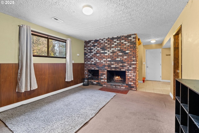 carpeted living room with a fireplace, wooden walls, and a textured ceiling